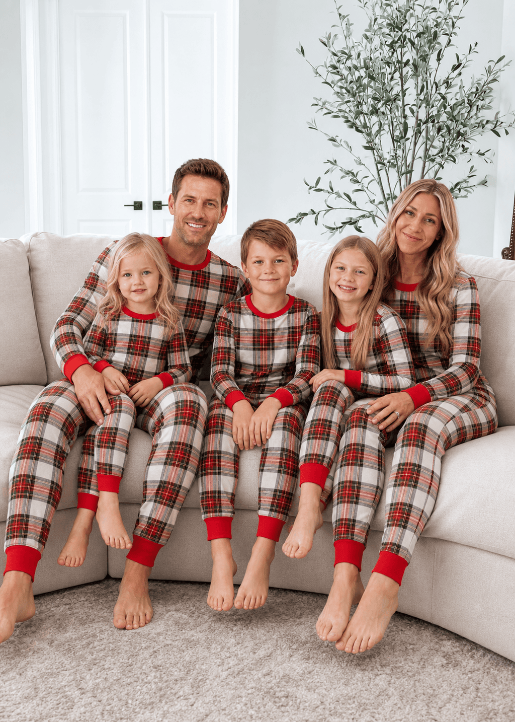 Family wearing matching cream and red tartan Christmas pyjamas with red ribbed cuffs