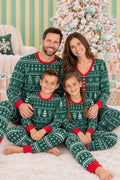 Family wearing matching green Fair Isle print Christmas pyjamas with red cuffs by a Christmas tree