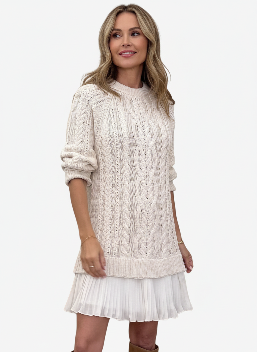 Woman wearing a cable knit jumper dress with ribbed crew neck and pleated mini hem