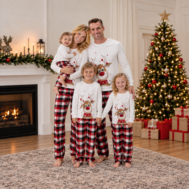Man in matching Christmas pajamas with reindeer print top and plaid pants by a fireplace