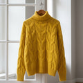 Women's chunky cable knit roll neck jumper on a wooden hanger