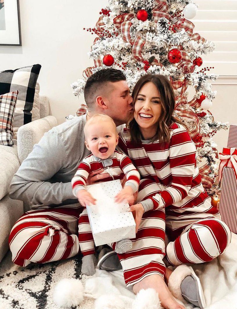 Family wearing matching red and white striped Christmas pyjamas with grey ribbed cuffs and a grey henley top - view 3
