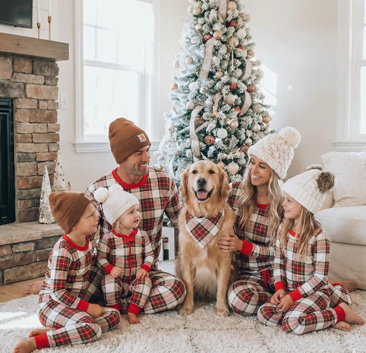 Family wearing matching cream and red tartan Christmas pyjamas with red ribbed cuffs