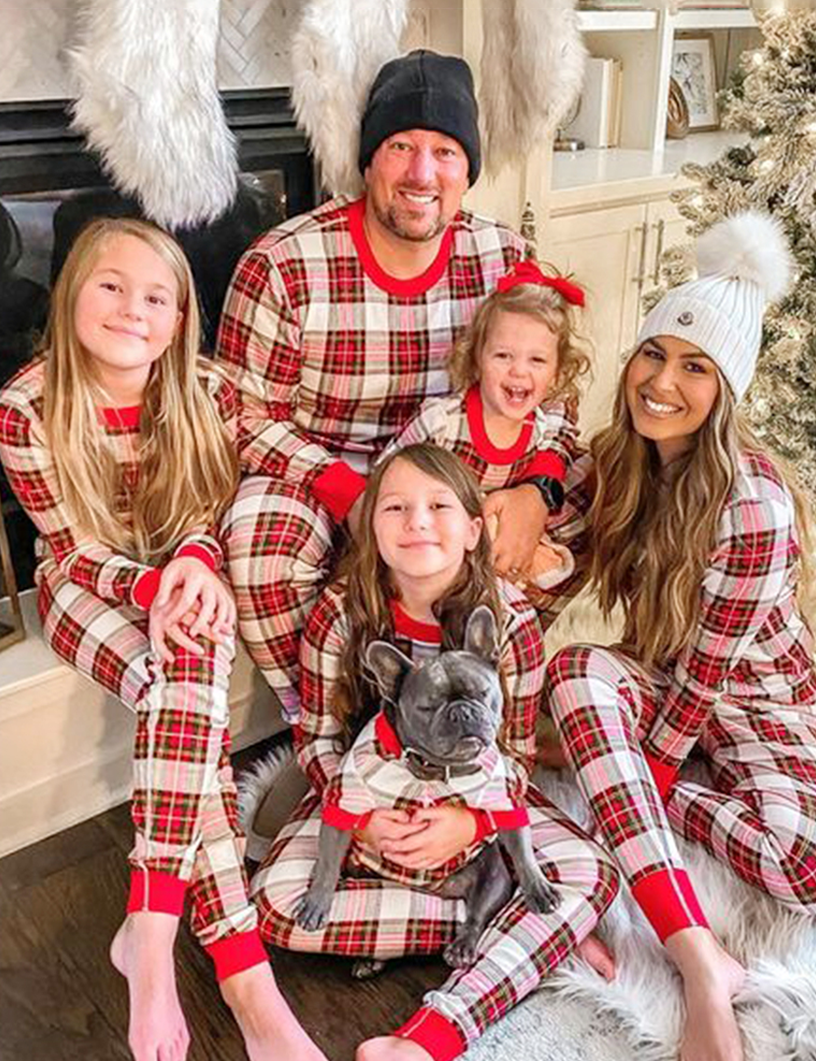 Family wearing matching red and white tartan Christmas pyjamas with red ribbed cuffs